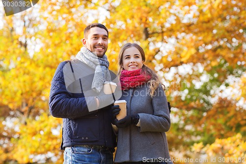 Image of smiling couple with coffee cups in autumn park