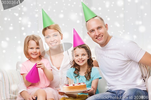 Image of happy family with two kids in party hats at home