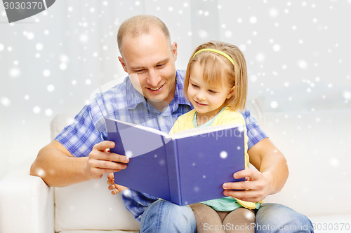 Image of smiling father and daughter with book at home