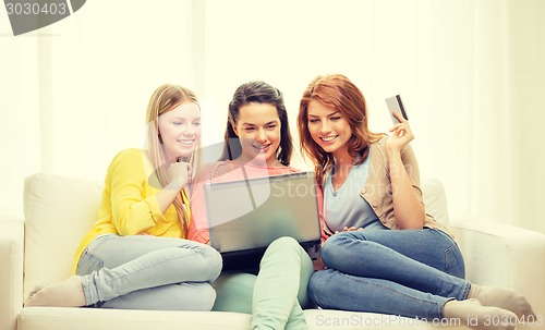 Image of smiling teenage girls with laptop and credit card