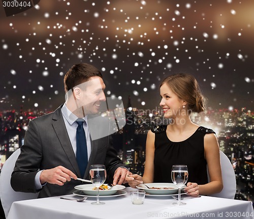 Image of smiling couple eating main course at restaurant