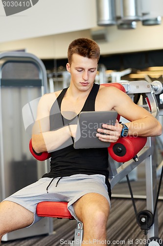 Image of young man with tablet pc computer in gym