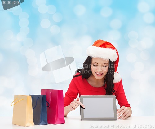 Image of smiling woman with shopping bags and tablet pc