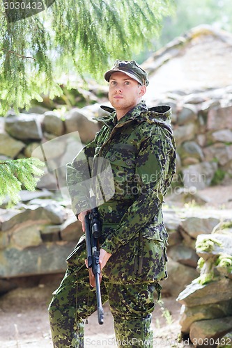 Image of young soldier or hunter with gun in forest