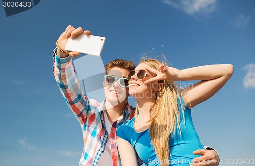 Image of smiling couple with smartphone making selfie