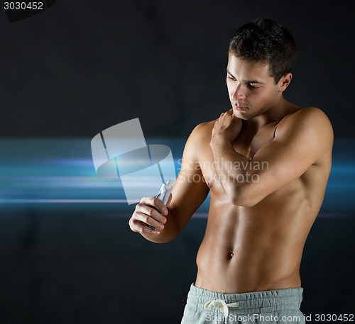 Image of young male bodybuilder applying pain relief gel