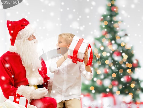 Image of smiling little boy with santa claus and gifts