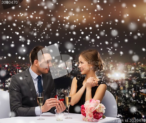 Image of smiling couple with red gift box at restaurant