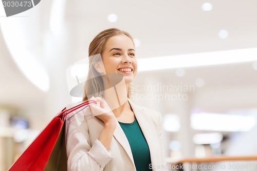 Image of happy young woman with shopping bags in mall