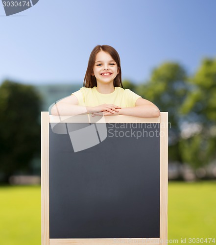 Image of happy little girl with blank blackboard