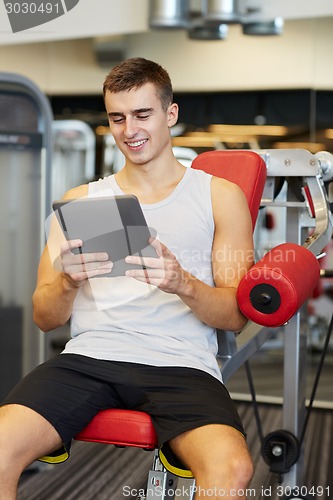 Image of smiling young man with tablet pc computer in gym