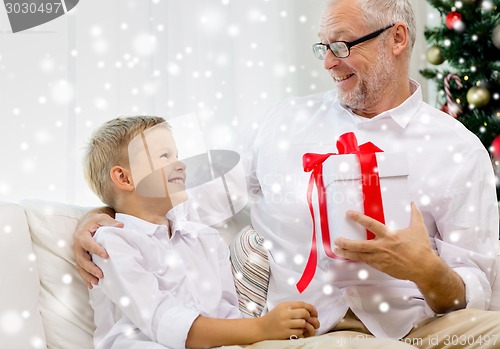 Image of smiling grandfather and grandson with gift box