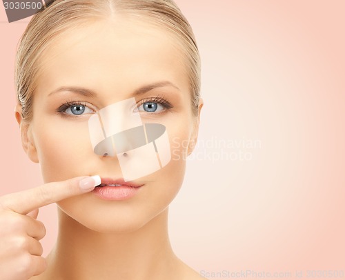 Image of beautiful young woman pointing finger to her lips