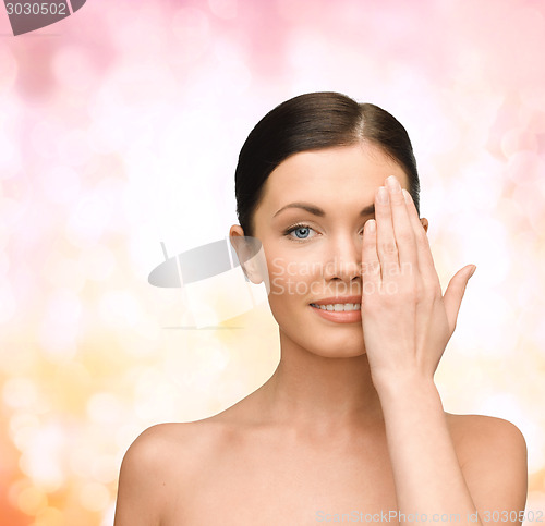 Image of smiling young woman covering face with hand
