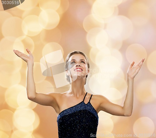 Image of smiling woman raising hands and looking up