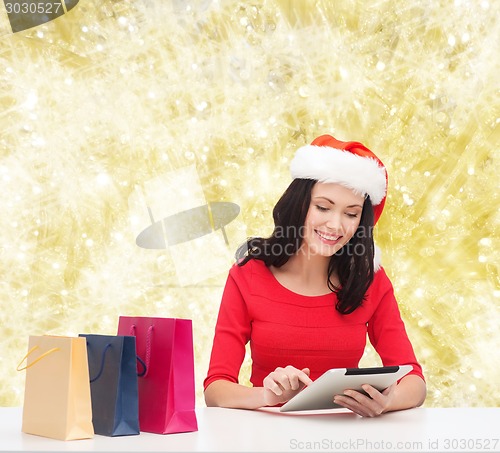 Image of smiling woman with shopping bags and tablet pc