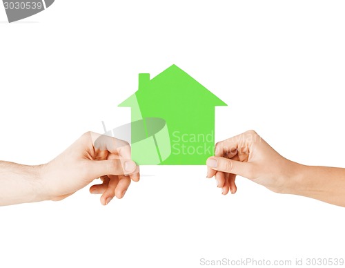 Image of man and woman hands with green paper house