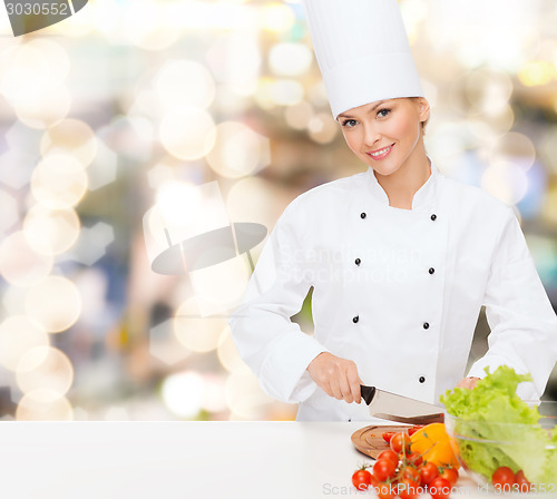 Image of smiling female chef chopping vegetables