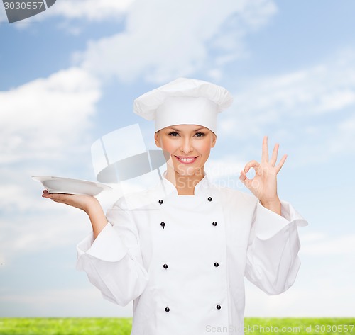 Image of smiling female chef with plate showing ok sign