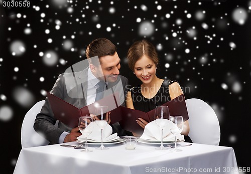 Image of smiling couple with menus at restaurant