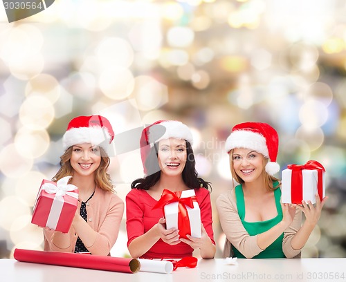 Image of smiling women in santa helper hats packing gifts