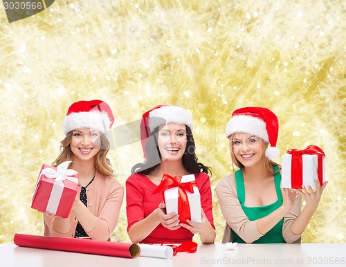 Image of smiling women in santa helper hats packing gifts