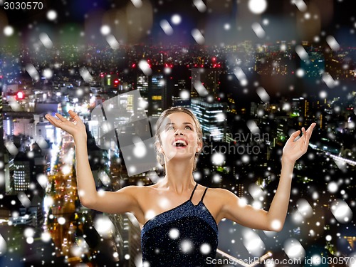 Image of smiling woman raising hands and looking up