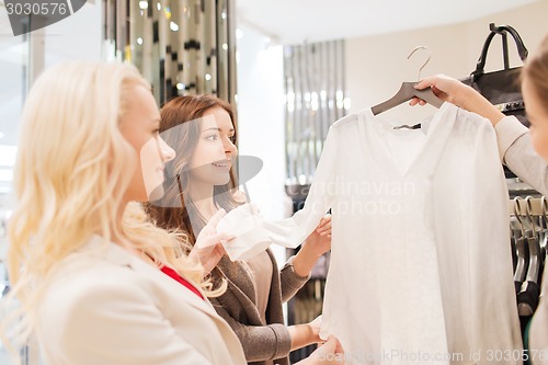 Image of happy young women choosing clothes in mall