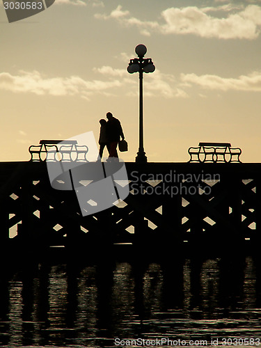 Image of Silhouette of Couple Walking On Pier At Dusk