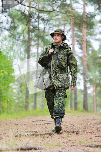 Image of young soldier or hunter with gun in forest