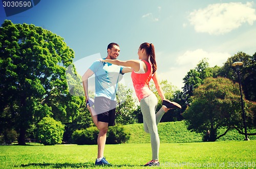 Image of smiling couple stretching outdoors