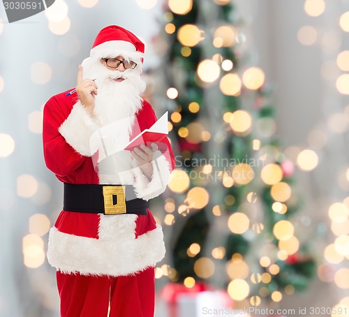 Image of man in costume of santa claus with notepad