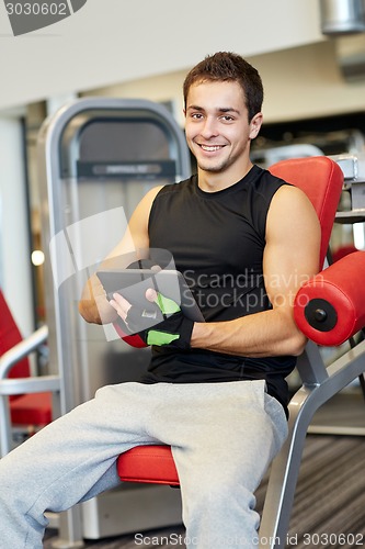 Image of smiling young man with tablet pc computer in gym
