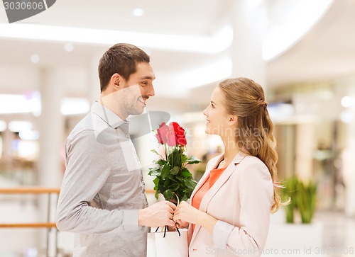 Image of happy young couple with flowers in mall