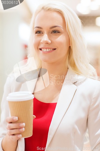 Image of happy young woman with coffee paper cup in mall