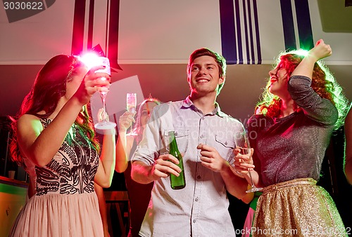 Image of smiling friends with wine glasses and beer in club