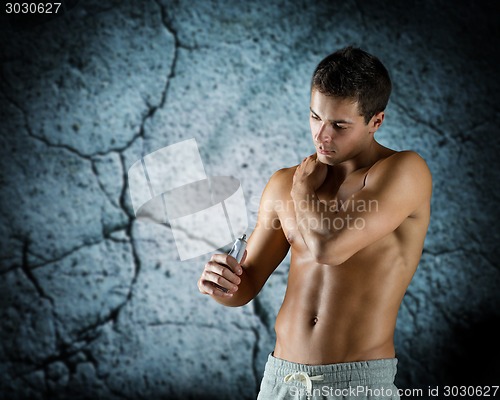 Image of young male bodybuilder applying pain relief gel