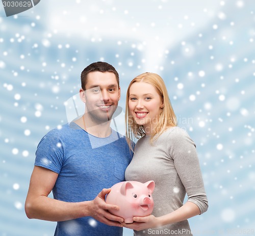 Image of smiling couple holding big piggy bank