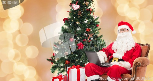 Image of man in costume of santa claus with laptop