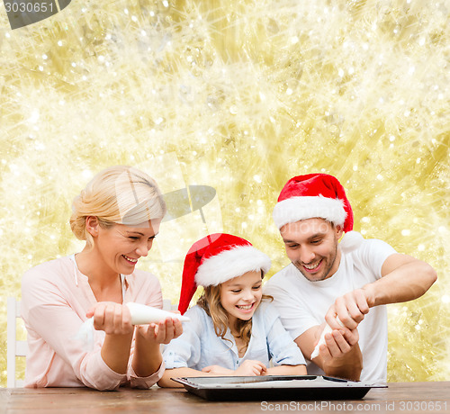 Image of happy family in santa helper hats cooking