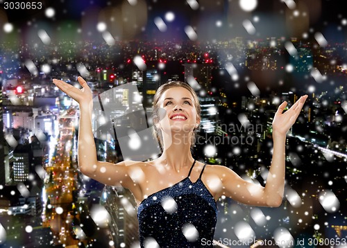 Image of smiling woman raising hands and looking up