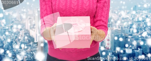 Image of close up of woman in pink sweater holding gift box