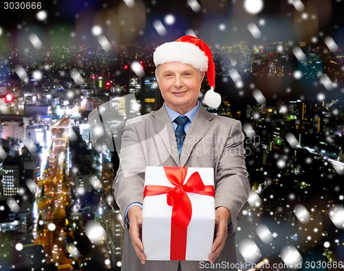 Image of smiling man in suit and santa helper hat with gift