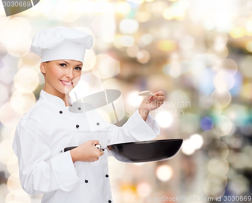 Image of smiling female chef with pan and spoon