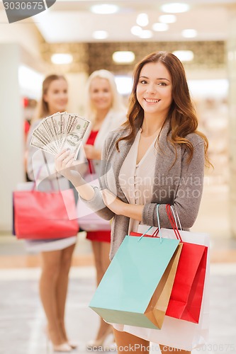 Image of young women with shopping bags and money in mall