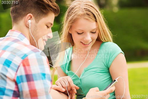 Image of smiling couple with smartphone and earphones