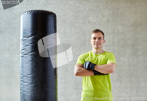 Image of man with boxing gloves and punching bag in gym