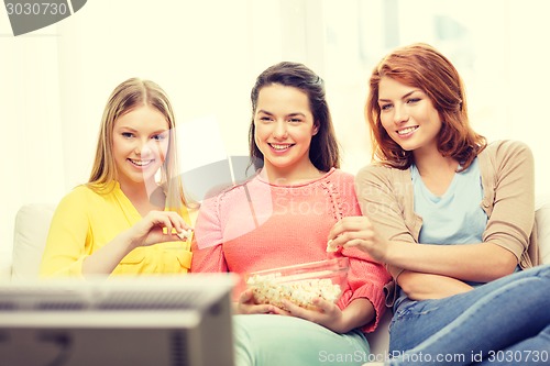 Image of three smiling teenage girl watching tv at home