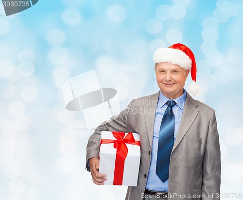 Image of smiling man in suit and santa helper hat with gift