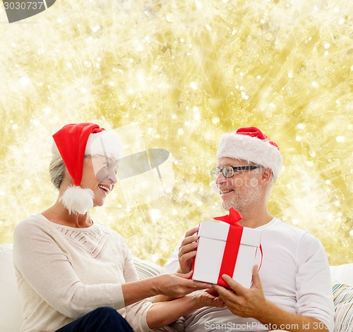 Image of happy senior couple with gift box at home